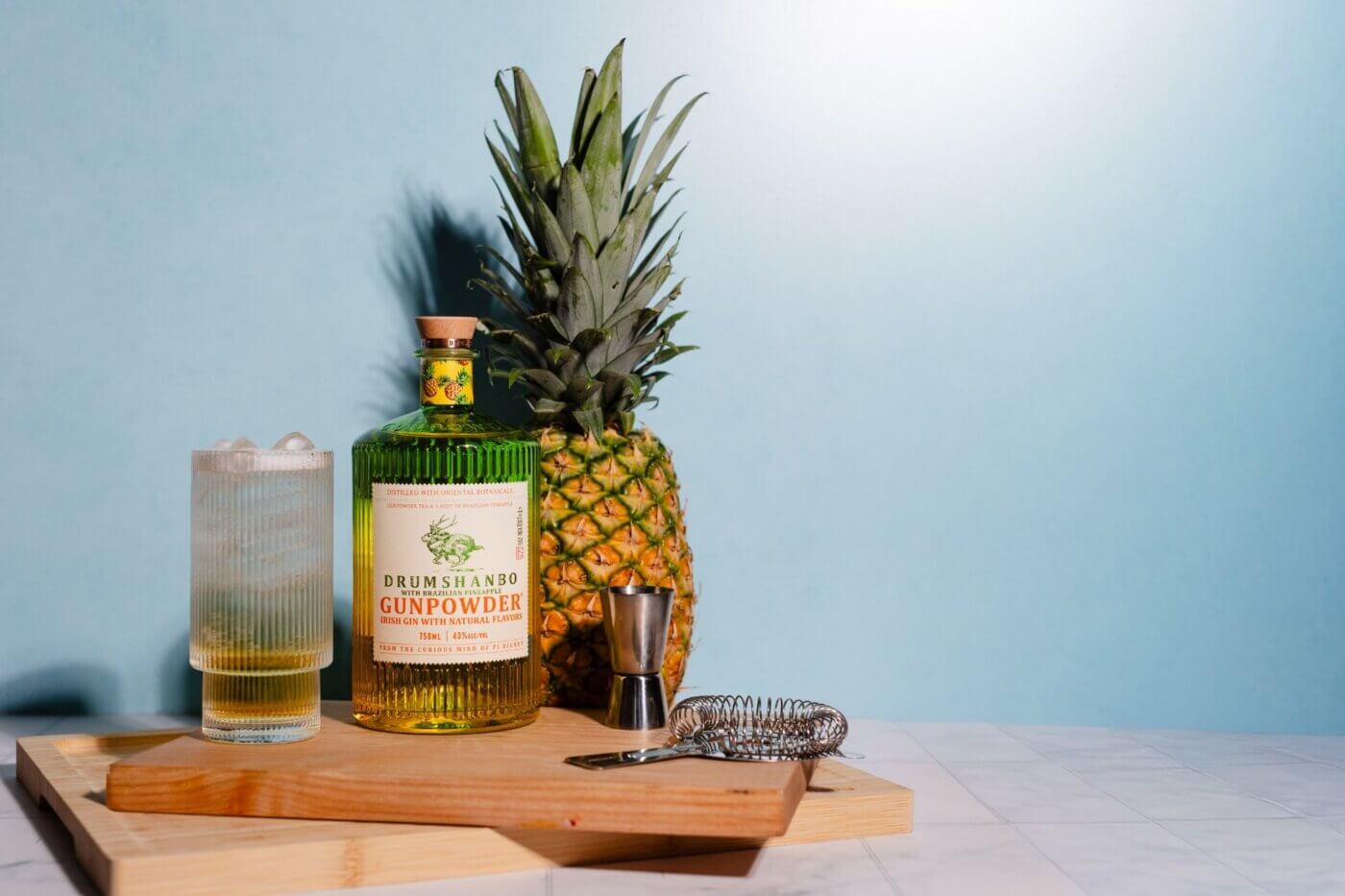 Drumshanbo Gunpowder Irish Gin with Brazilian Pineapple bottle with cup of drink filled up