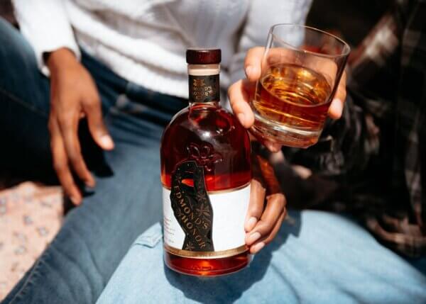 Person holding Bottle of Edmond's Honor bourbon and glass filled up in honor of national bourbon heritage month