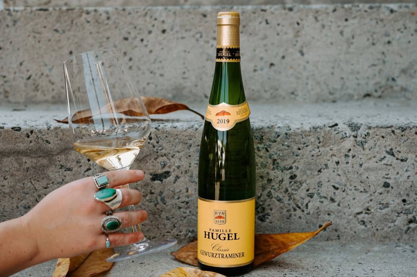 Hugel Classic Gewürztraminer wine bottle with hand holding wine glass